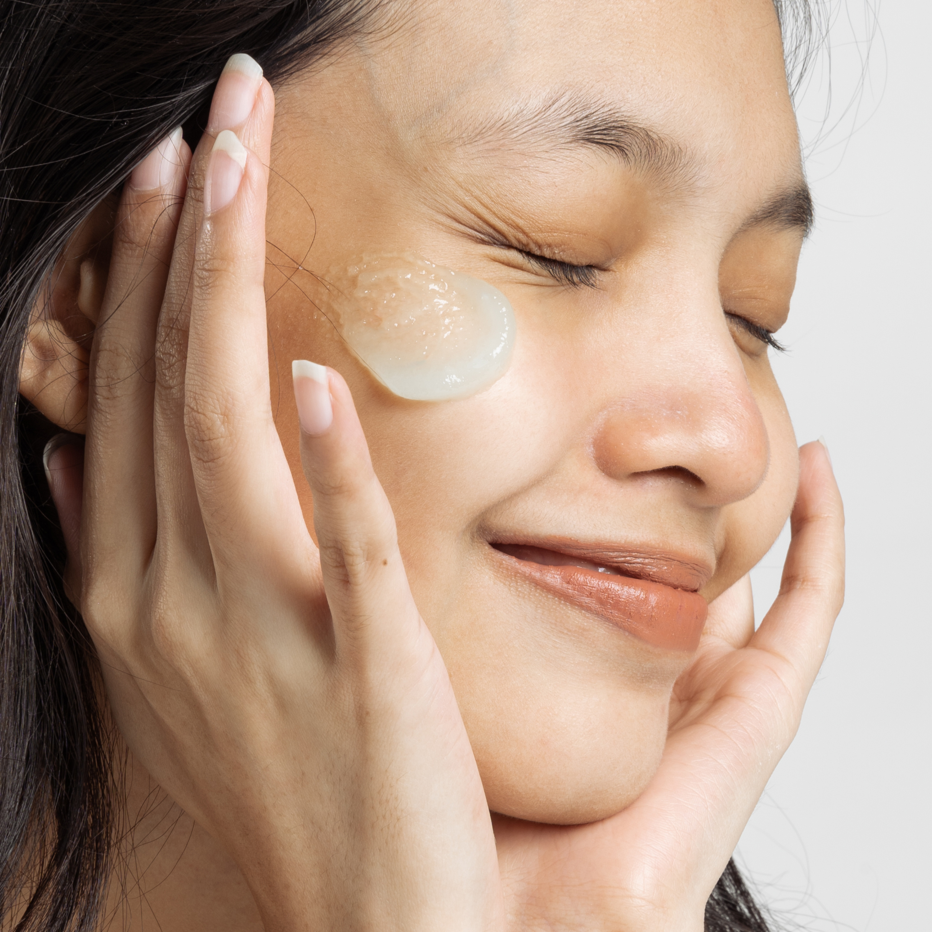 woman applying niacinamide serum moisturizer on her face and smiling. skinsetgo skincare